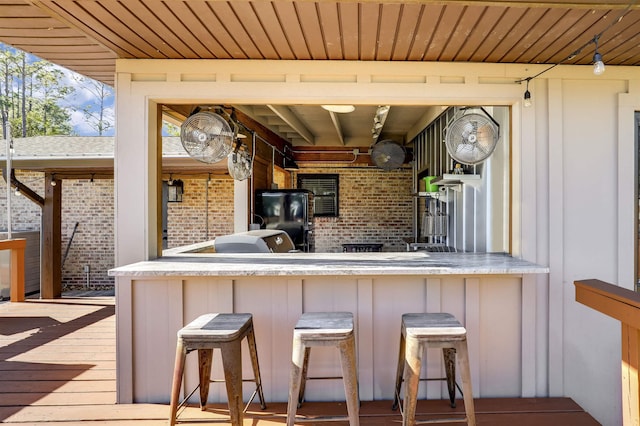 kitchen featuring a kitchen bar, kitchen peninsula, wood ceiling, and brick wall