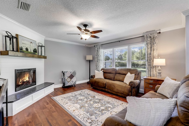 living room with dark hardwood / wood-style floors, ceiling fan, ornamental molding, and a textured ceiling