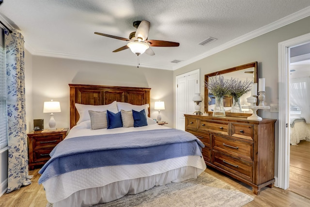 bedroom featuring ceiling fan, ornamental molding, a textured ceiling, light hardwood / wood-style floors, and a closet