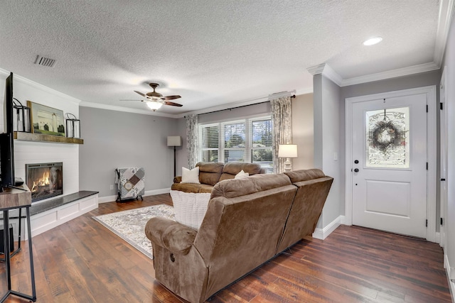 living room with crown molding, a large fireplace, ceiling fan, and dark hardwood / wood-style floors