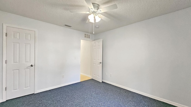 unfurnished bedroom featuring dark colored carpet, a textured ceiling, baseboards, and a ceiling fan