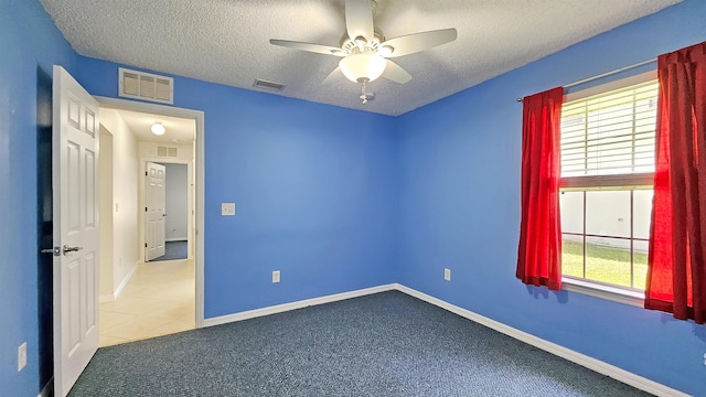 unfurnished room with a textured ceiling, ceiling fan, carpet, and baseboards