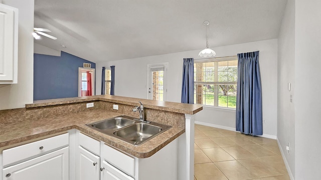 kitchen with lofted ceiling, a sink, a peninsula, baseboards, and ceiling fan