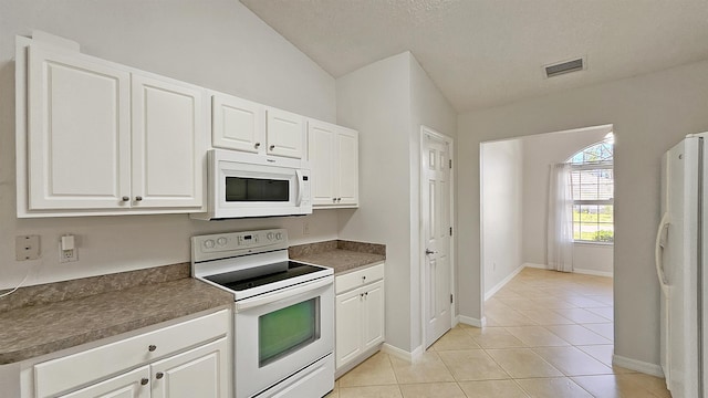 kitchen with white appliances, light tile patterned floors, white cabinetry, and lofted ceiling