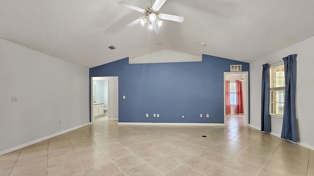 spare room with lofted ceiling, ceiling fan, light tile patterned flooring, a textured ceiling, and baseboards