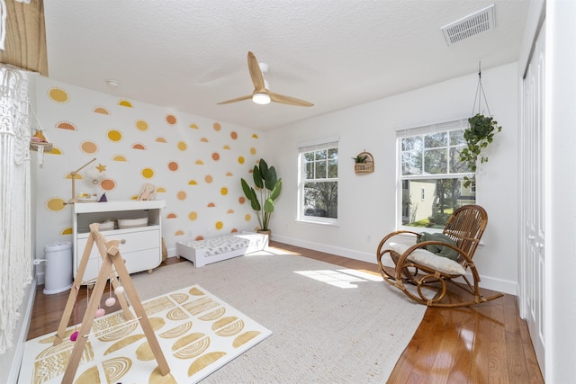 1036 Saltwater Cir, Saint Augustine, FL 32080 - bedroom with wallpapered walls, wood finished floors, a textured ceiling, and a ceiling fan
