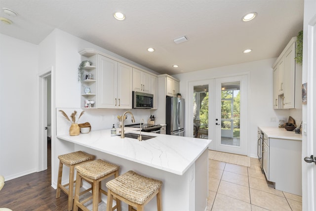 1036 Saltwater Cir, Saint Augustine, FL 32080 - kitchen with stainless steel appliances, french doors, open shelves, a peninsula, and recessed lighting