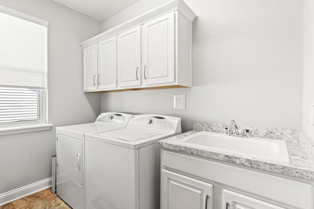 clothes washing area with cabinets, sink, and washing machine and clothes dryer