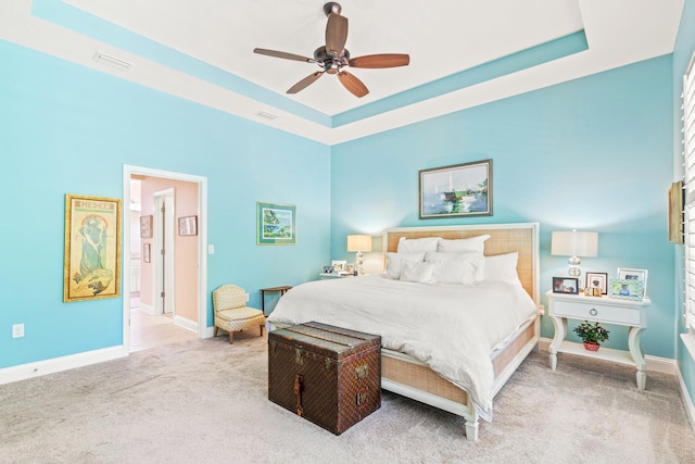 bedroom with carpet, ceiling fan, and a raised ceiling