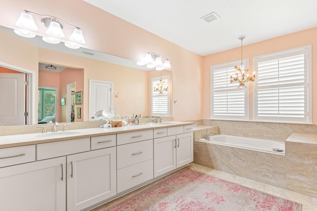 bathroom featuring vanity, a relaxing tiled tub, and a notable chandelier