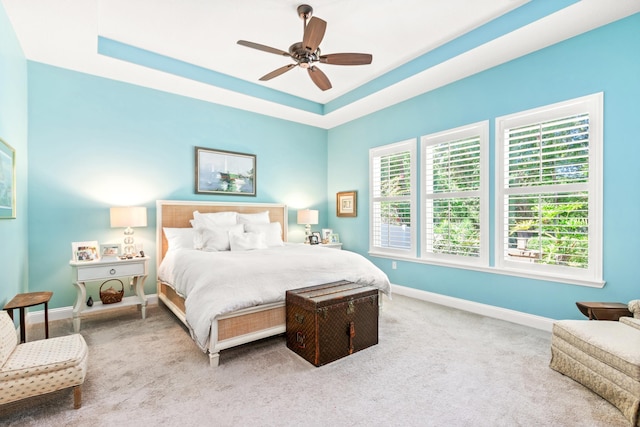 carpeted bedroom featuring a tray ceiling and ceiling fan