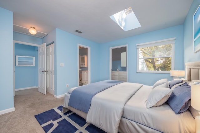 carpeted bedroom with a skylight and ensuite bath