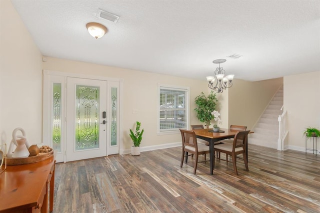 dining space with dark hardwood / wood-style flooring, a notable chandelier, and a textured ceiling