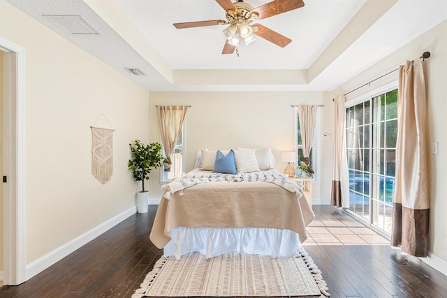 bedroom with a tray ceiling, hardwood / wood-style floors, and access to outside