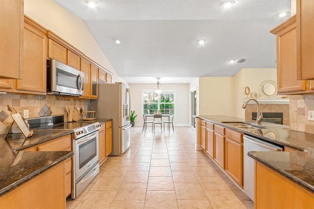 kitchen featuring vaulted ceiling, light tile patterned flooring, pendant lighting, sink, and stainless steel appliances