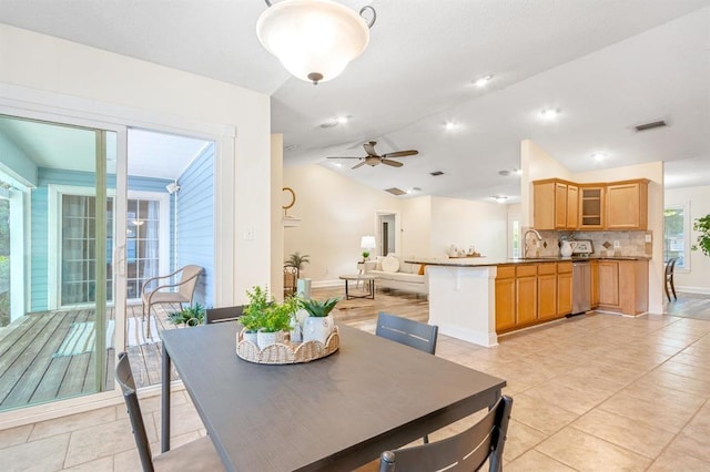 tiled dining space with lofted ceiling, sink, and ceiling fan