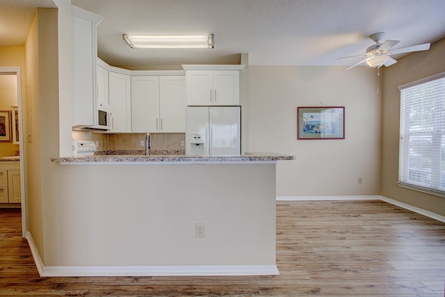 20102 Harbour Vista Cir, Saint Augustine, FL 32080 - kitchen featuring white fridge with ice dispenser, a peninsula, a ceiling fan, light wood-type flooring, and backsplash