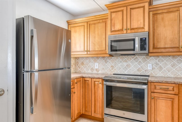 8550 S A1A # 331, Saint Augustine, FL 32080 - kitchen featuring appliances with stainless steel finishes, decorative backsplash, light stone countertops, and brown cabinets
