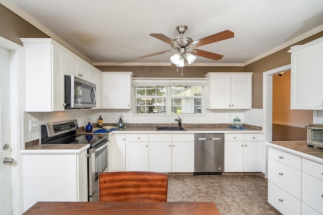 kitchen with ceiling fan, sink, stainless steel appliances, crown molding, and white cabinets