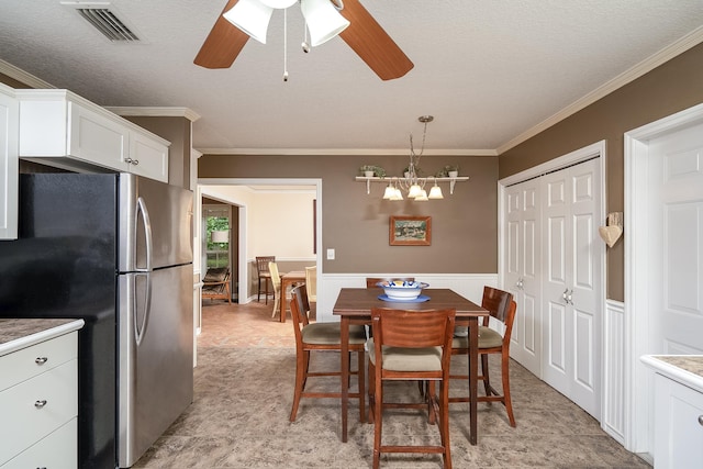 dining space featuring a textured ceiling, ceiling fan, and crown molding