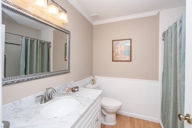 bathroom with vanity, a textured ceiling, crown molding, wood-type flooring, and toilet