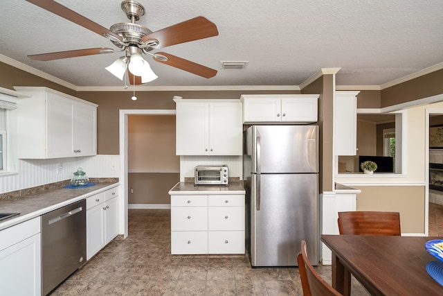 kitchen with white cabinets, crown molding, stainless steel appliances, and a textured ceiling