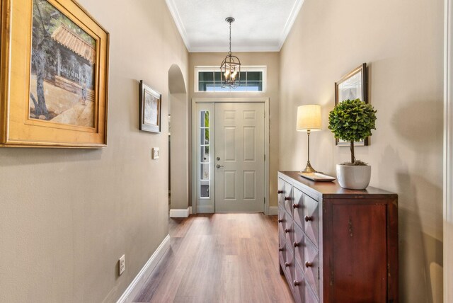 303 S Ocean Trace Rd, Saint Augustine, FL 32080 - foyer with crown molding, wood finished floors, arched walkways, baseboards, and a chandelier