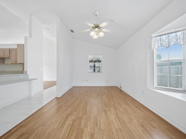 spare room featuring ceiling fan, a healthy amount of sunlight, vaulted ceiling, and light hardwood / wood-style flooring