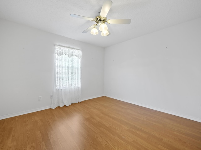 spare room with a textured ceiling, ceiling fan, and light hardwood / wood-style flooring