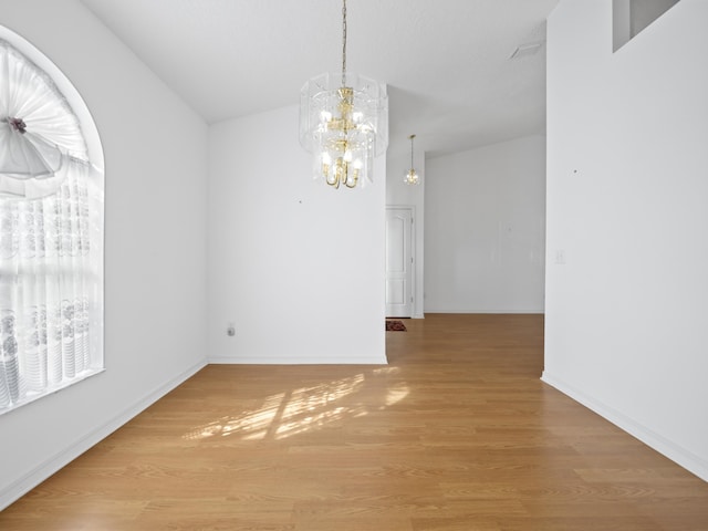 unfurnished dining area featuring a chandelier and light wood-type flooring