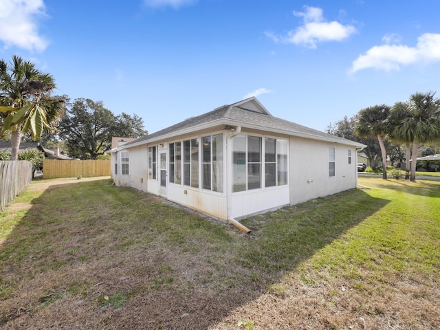 rear view of house featuring a sunroom and a yard