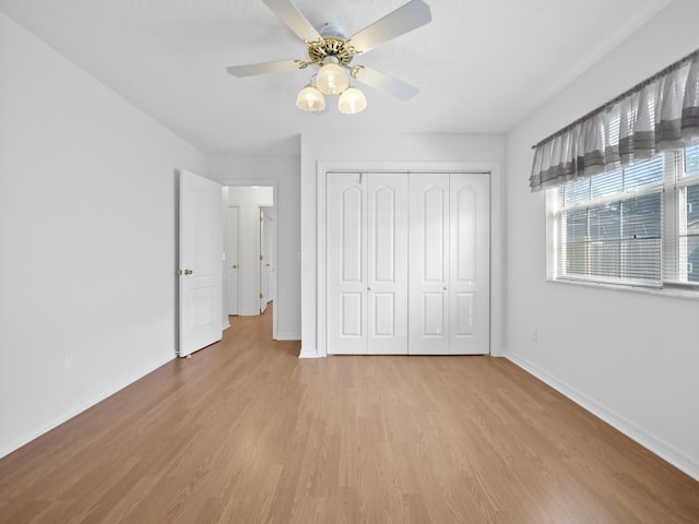 unfurnished bedroom featuring ceiling fan, light hardwood / wood-style floors, and a closet