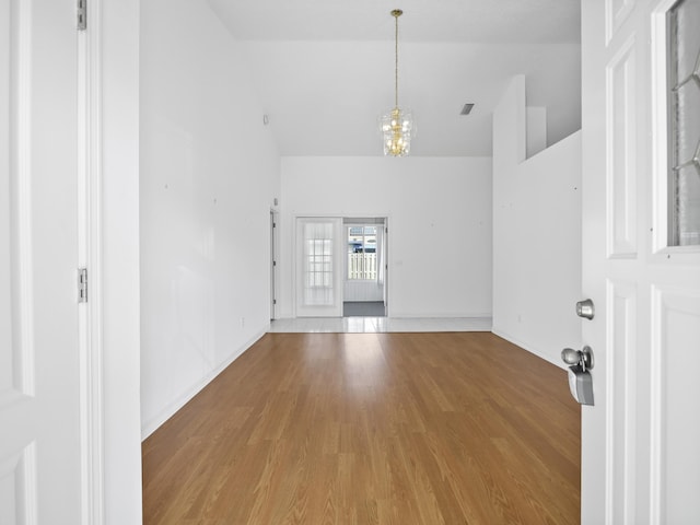 unfurnished room featuring hardwood / wood-style flooring, high vaulted ceiling, and a chandelier