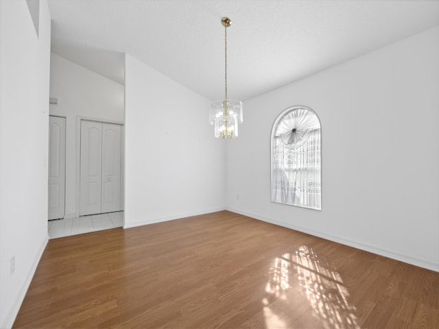 spare room with wood-type flooring, lofted ceiling, and a chandelier