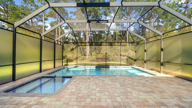 view of pool featuring an in ground hot tub, glass enclosure, and a patio area