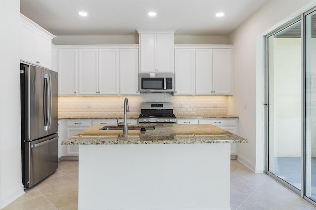 kitchen with appliances with stainless steel finishes, white cabinets, a center island with sink, and sink