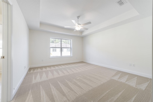 carpeted spare room featuring ceiling fan and a tray ceiling