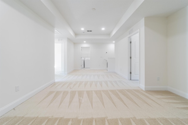 carpeted empty room with a raised ceiling