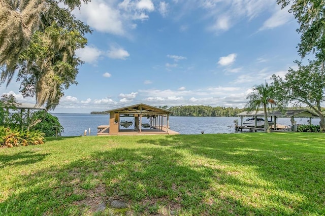view of dock with a lawn and a water view