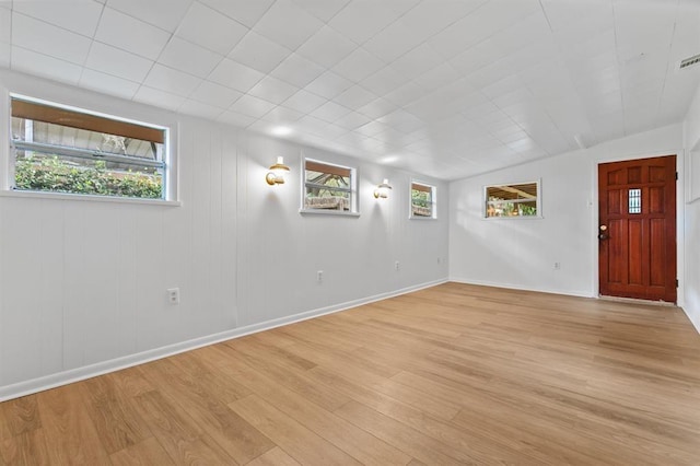 empty room featuring light wood-style floors, baseboards, and visible vents