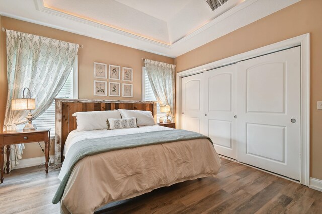 bedroom featuring hardwood / wood-style floors, a raised ceiling, and a closet