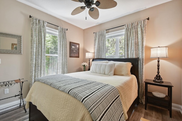 bedroom with ceiling fan, dark wood-type flooring, and multiple windows