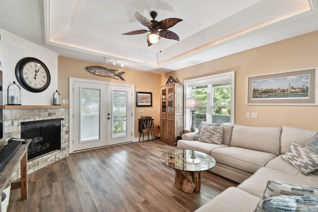 living room with a raised ceiling, wood-type flooring, a fireplace, and french doors