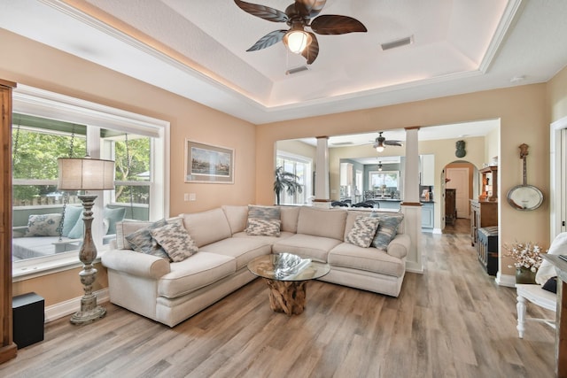 living room with light wood-type flooring and a tray ceiling