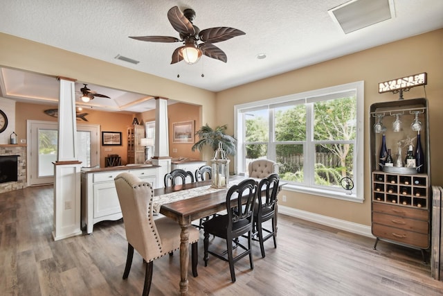 dining area with a tray ceiling, ceiling fan, light hardwood / wood-style floors, and a textured ceiling