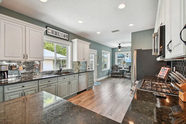 kitchen featuring kitchen peninsula, light wood-type flooring, high end appliances, sink, and white cabinets