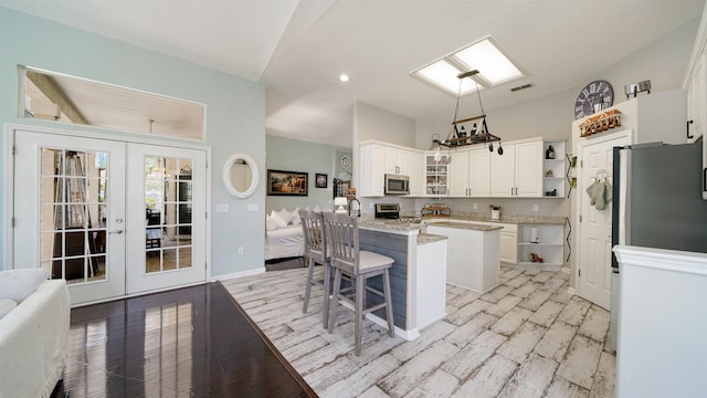 700 N Indigo Ter, Saint Johns, FL 32259 - kitchen with stainless steel appliances, open shelves, french doors, a kitchen bar, and white cabinetry