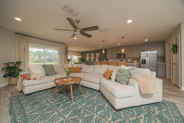 living room with ceiling fan and light wood-type flooring