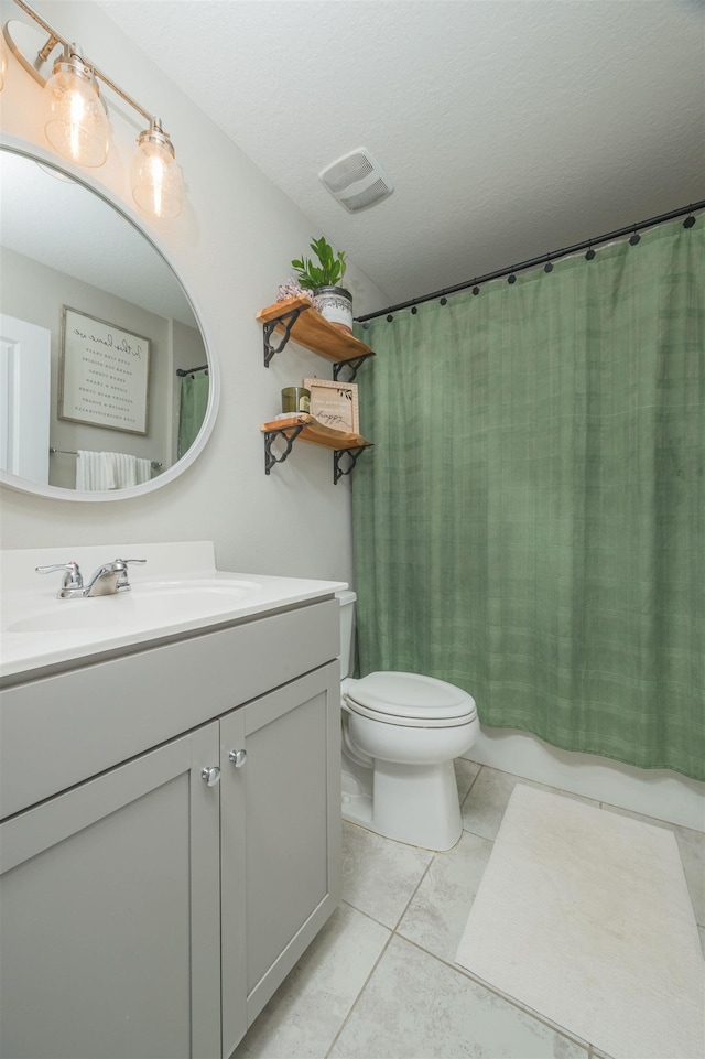 bathroom featuring vanity, tile patterned flooring, a textured ceiling, and toilet