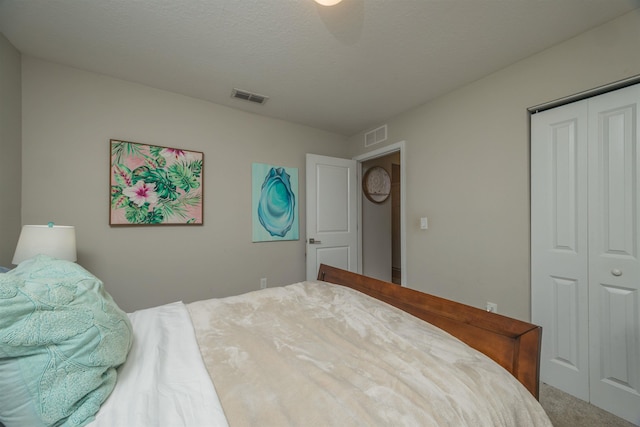 carpeted bedroom with a textured ceiling and a closet